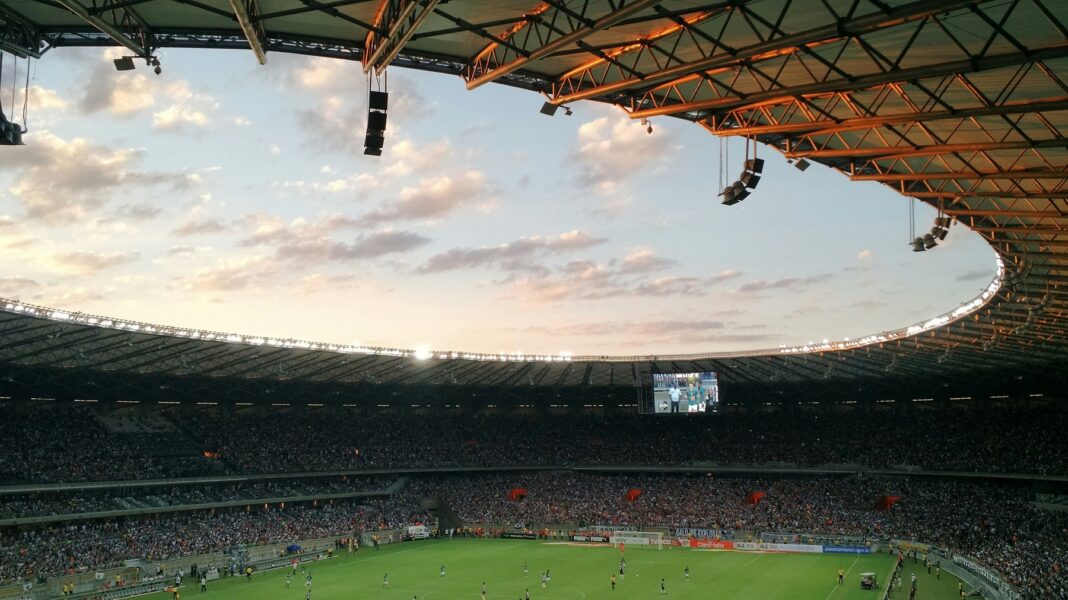 marcos-moraes-rFehnP5wN4Q-unsplash Um estádio de futebol com uma multidão assistindo a uma partida